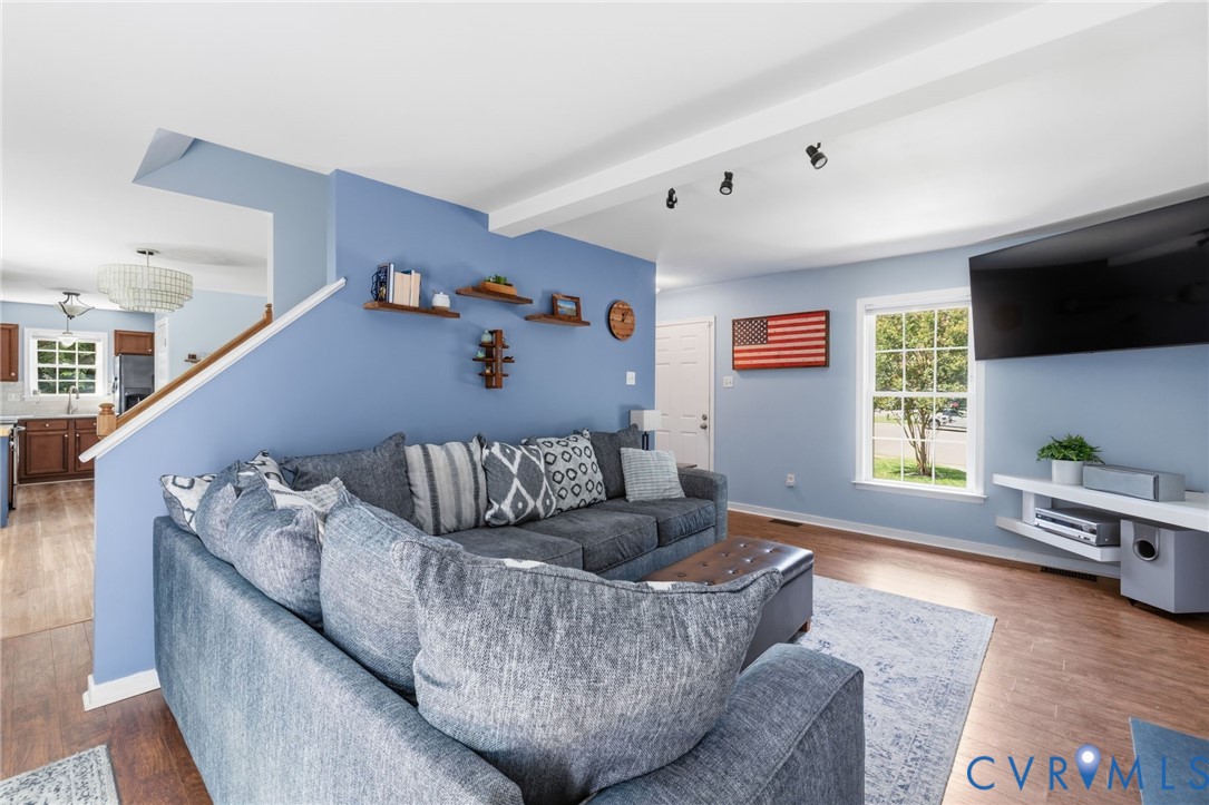 Open-concept living space featuring wood-finish flooring, recessed lighting, and a white-trimmed window