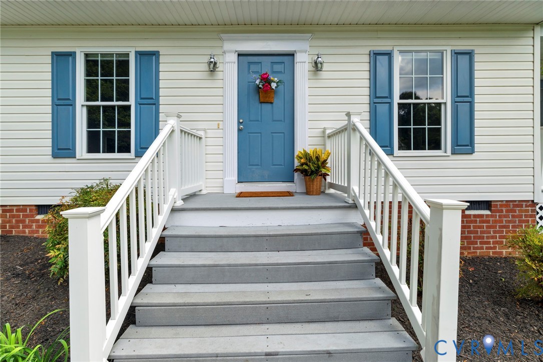 Front entry with white siding and brick foundation