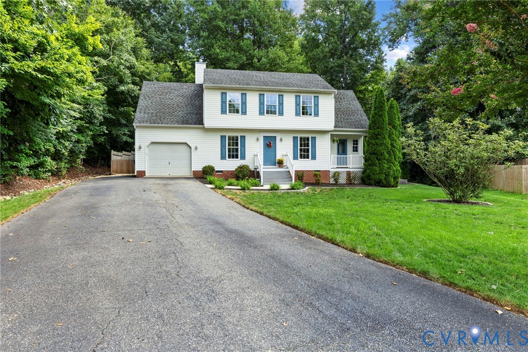 Two-story residence featuring white siding, blue window shutters, an attached garage, a front porch with white columns, and a paved driveway
