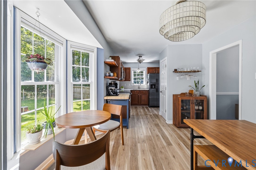 Bay window with white trim, wood-finish flooring, recessed lighting, and a tiered decorative light fixture