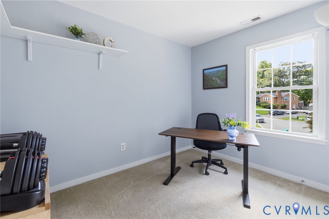 Carpeted flooring, a double-hung window with a wood-finish frame, and a wall-mounted display shelf