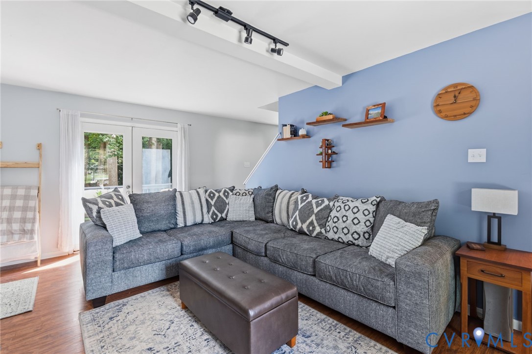 Wood-finish flooring, white double French doors, track lighting, and built-in floating shelves