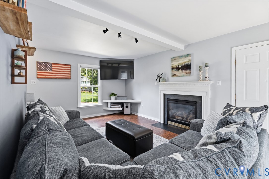 Living area featuring a gas fireplace with a white mantel, wood-finish flooring, and white trim