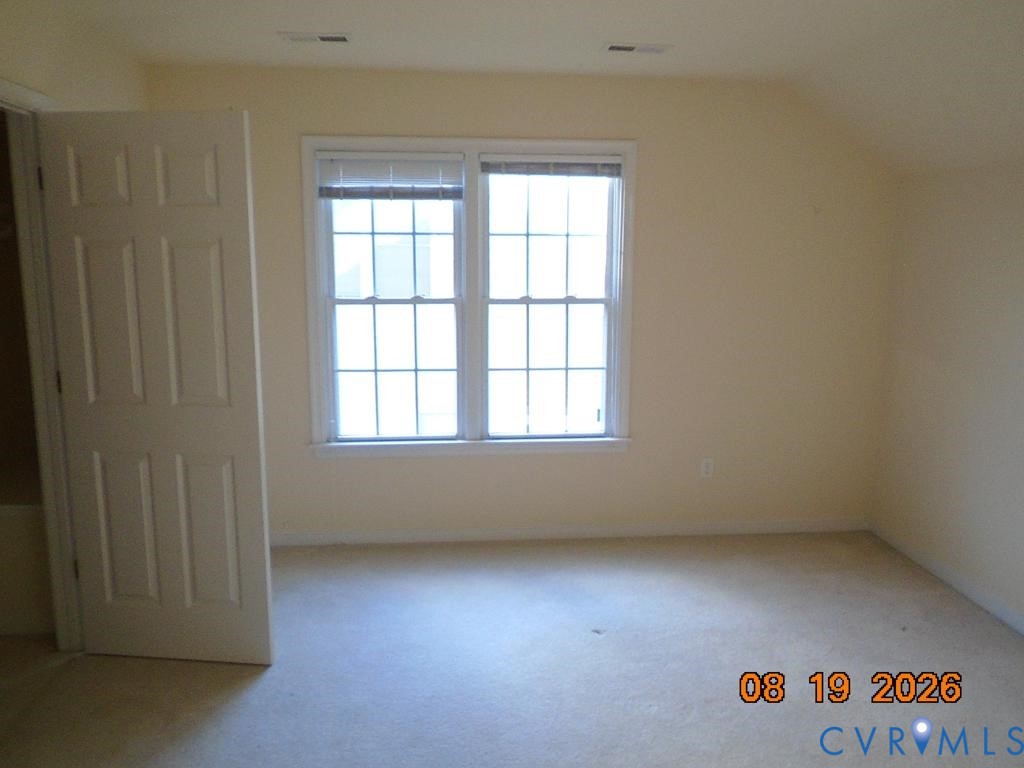 Dual windows with white blinds, neutral wall paint, and light-colored carpeting