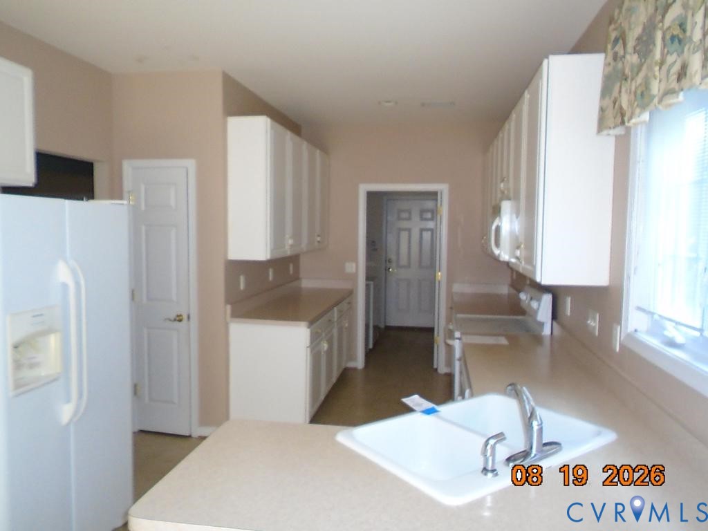 Kitchen with white cabinetry, light-toned countertops, and a double-basin sink