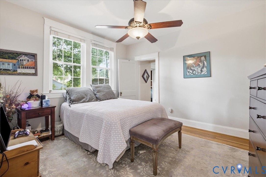 Dual windows, wood-finish flooring, ceiling fan with integrated lighting, and white trim