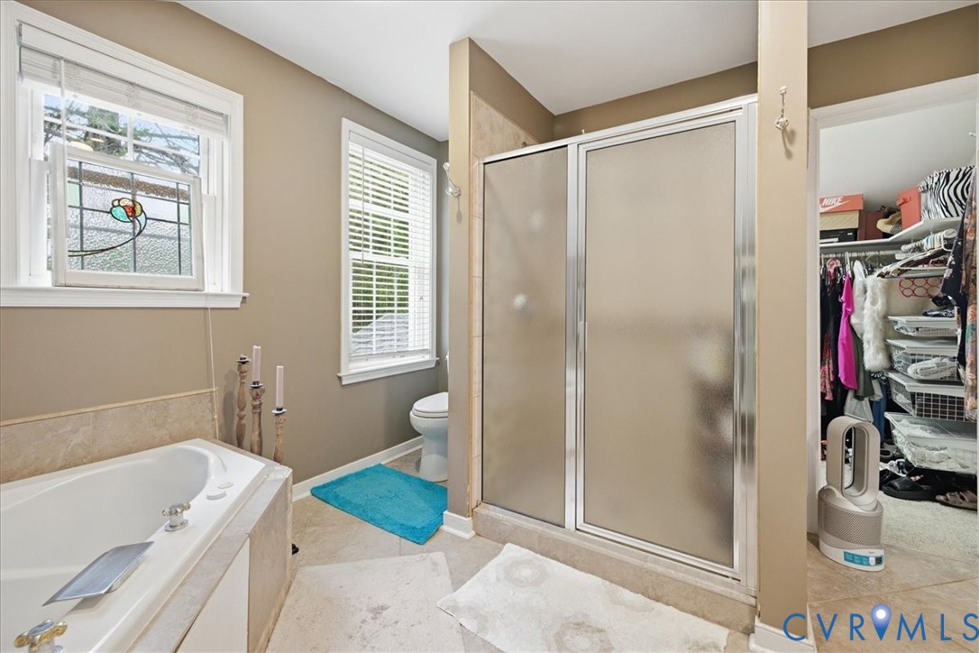 Built-in soaking tub, glass-enclosed shower, dual windows with blinds, and tiled flooring