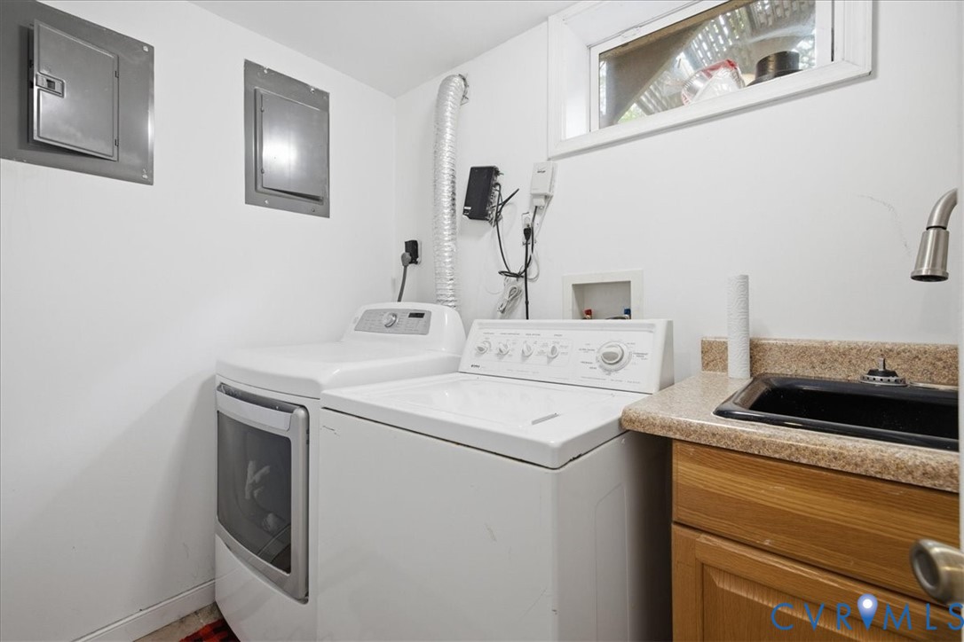 Laundry area with a built-in utility sink, wood-finish cabinetry, and a window