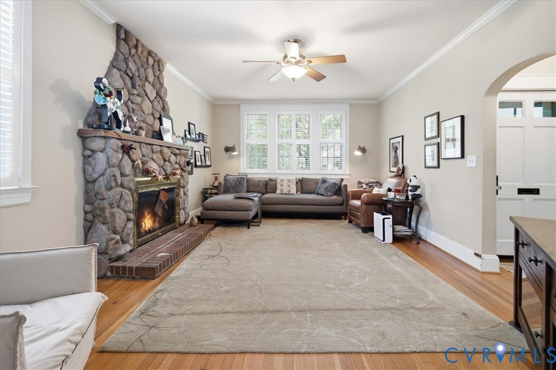 Stone look fireplace with a brick hearth, hardwood flooring, ceiling fan, and multiple windows Stone look fireplace with a brick hearth, hardwood flooring, ceiling fan, and multiple windows