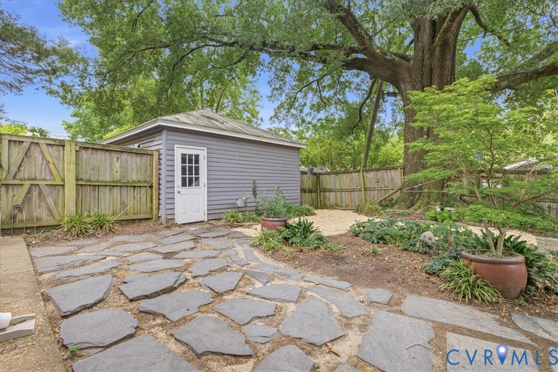 Flagstone patio with an expansive wooden privacy fence and a detached storage building on lovely treed lot.
