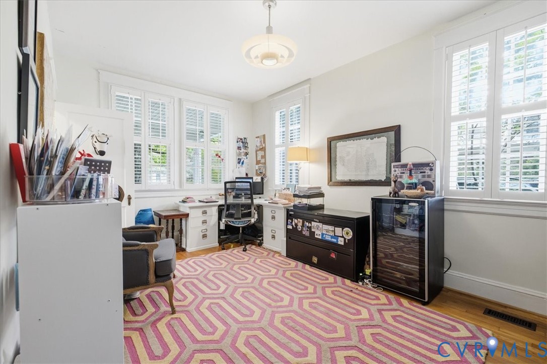 Main floor used in photo as office with hardwood flooring, multiple windows with plantation shutters, ceiling-mounted light fixture