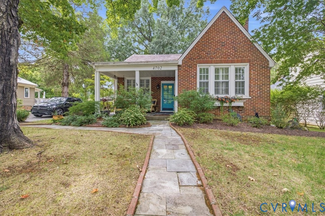 Brick exterior with a gabled roofline, covered porch, and mature landscaping Brick exterior with a gabled roofline, covered porch, and mature landscaping
