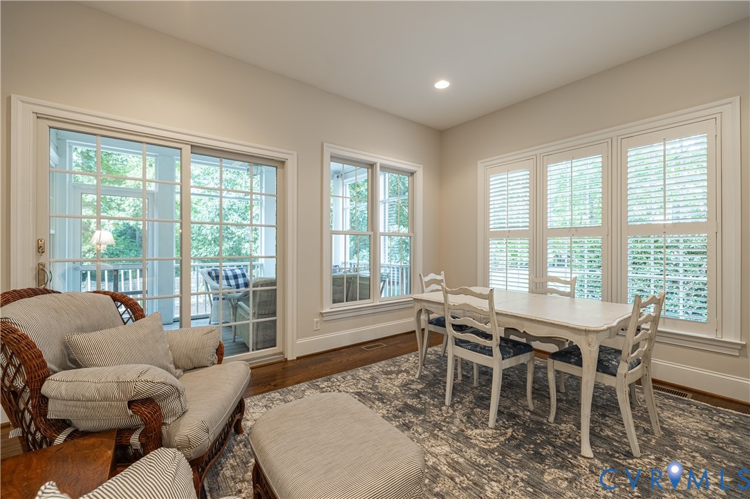 Sliding glass patio door, multiple windows with plantation shutters, recessed lighting, and wood-finish flooring