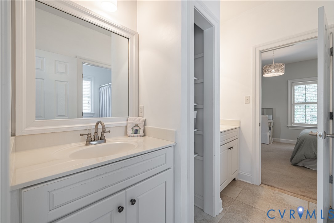 Shared bath-vanity with an integrated sink and brushed nickel faucet, a built-in storage niche, and tile flooring