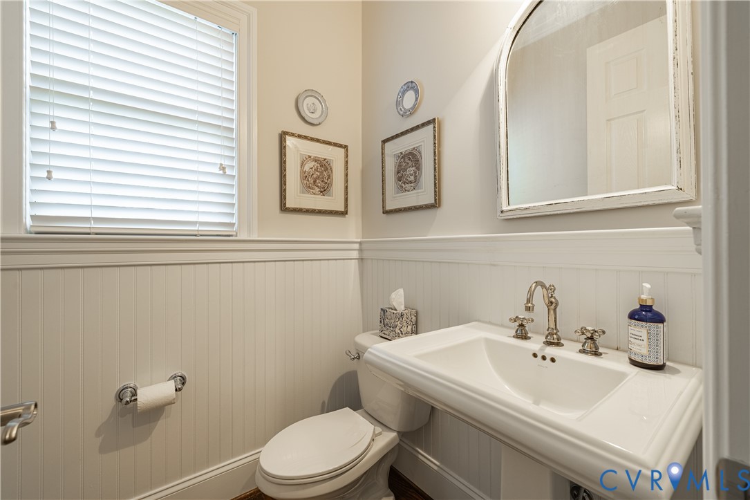 Pedestal sink, beadboard wainscoting, and a decorative framed mirror