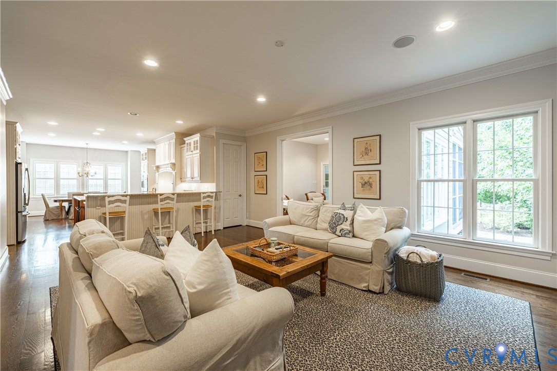 Open-concept living space with dark wood-finish flooring, recessed lighting, and crown molding