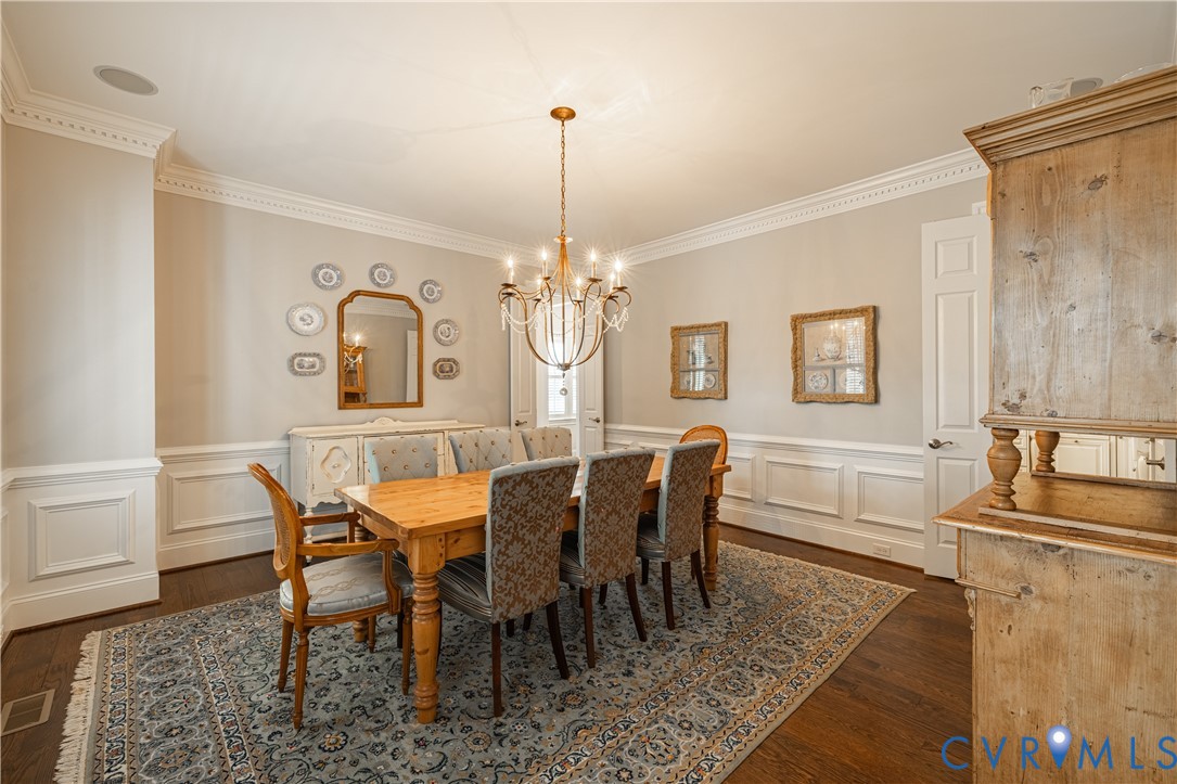 Hardwood flooring, extensive crown molding, wainscoting, recessed ceiling lighting, and a chandelier