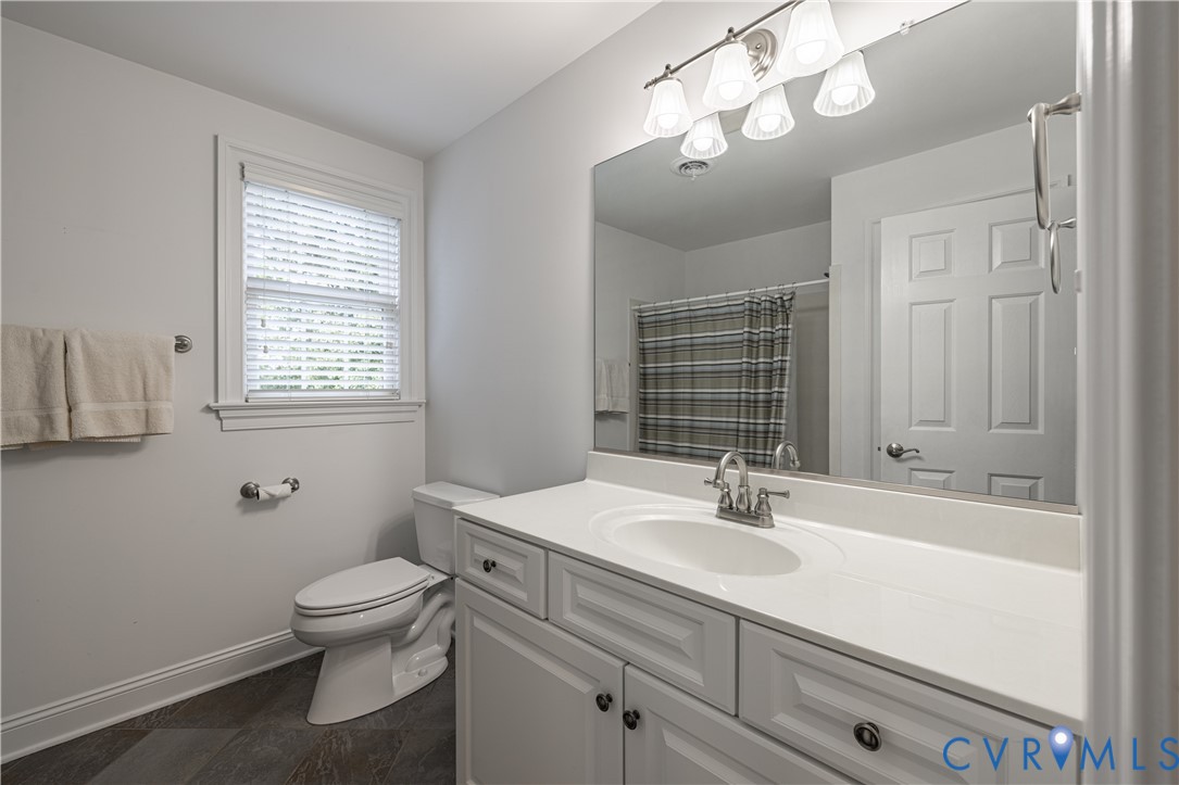 Vanity with a single basin sink, large wall mirror, and overhead vanity lighting