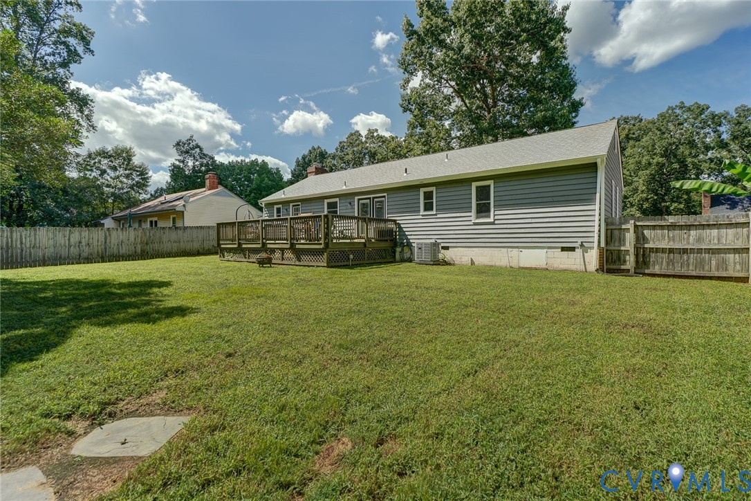 Expansive backyard featuring a spacious wood deck, gray horizontal siding, and a privacy fence