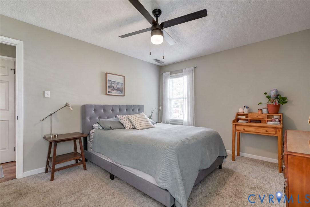 Neutral-toned walls, textured carpeting, and a ceiling fan with integrated lighting