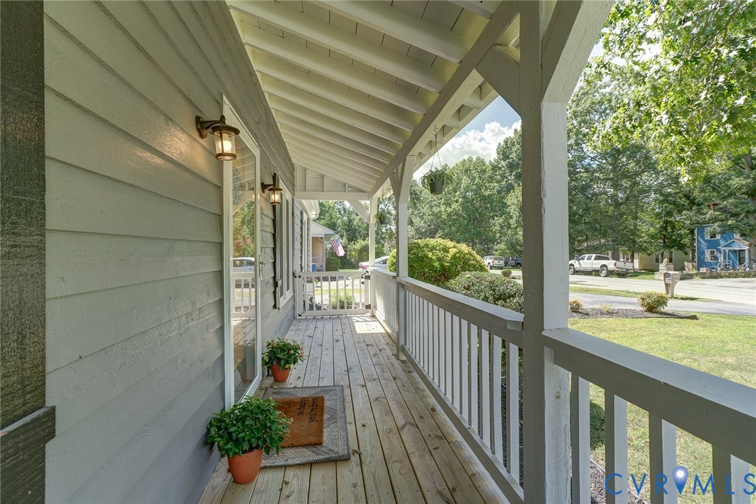 Covered front porch with wood flooring and white railing