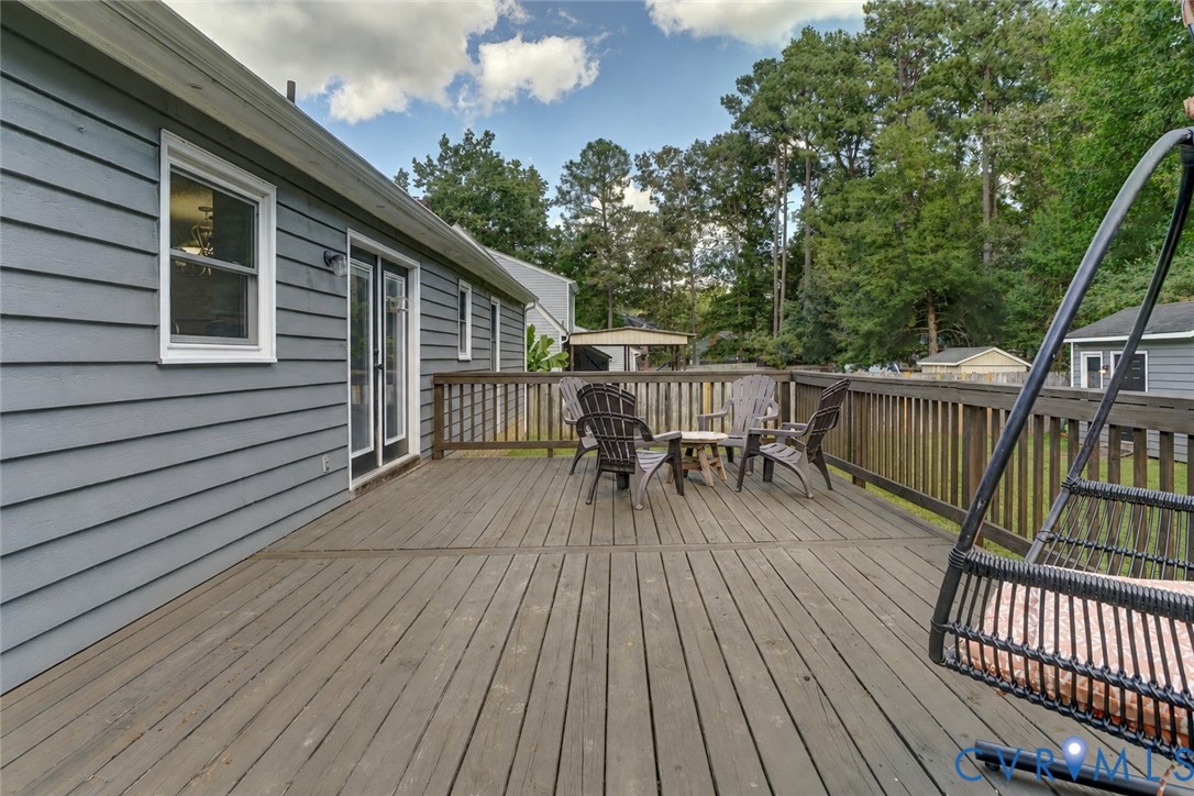 Expansive wooden deck with a wooden railing and double glass doors