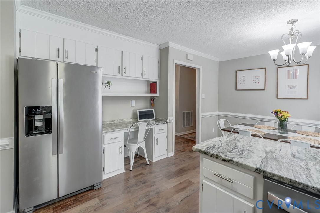 Kitchen featuring wood-finish flooring, white cabinetry, integrated desk space, and stone countertops