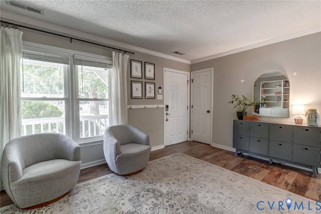 Wood-finish flooring, white trim, and crown molding