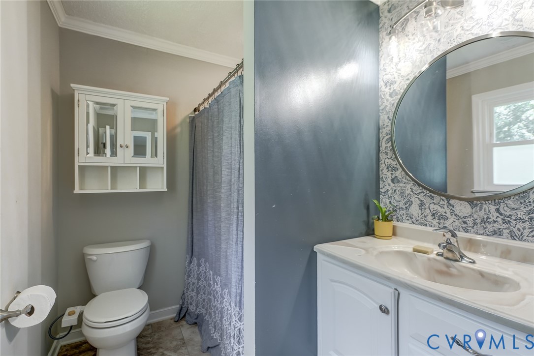 Bathroom featuring a vanity with an integrated sink, round mirror, and a wall-mounted medicine cabinet
