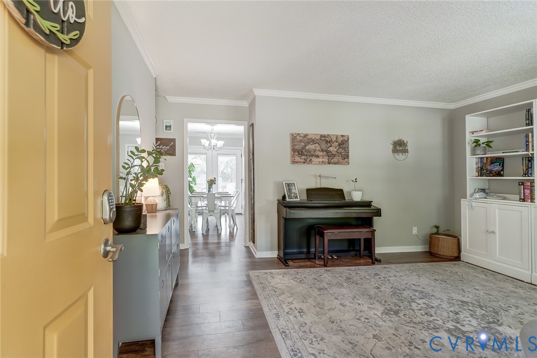 Wood-finish flooring throughout, white crown molding, and a built-in white shelving unit