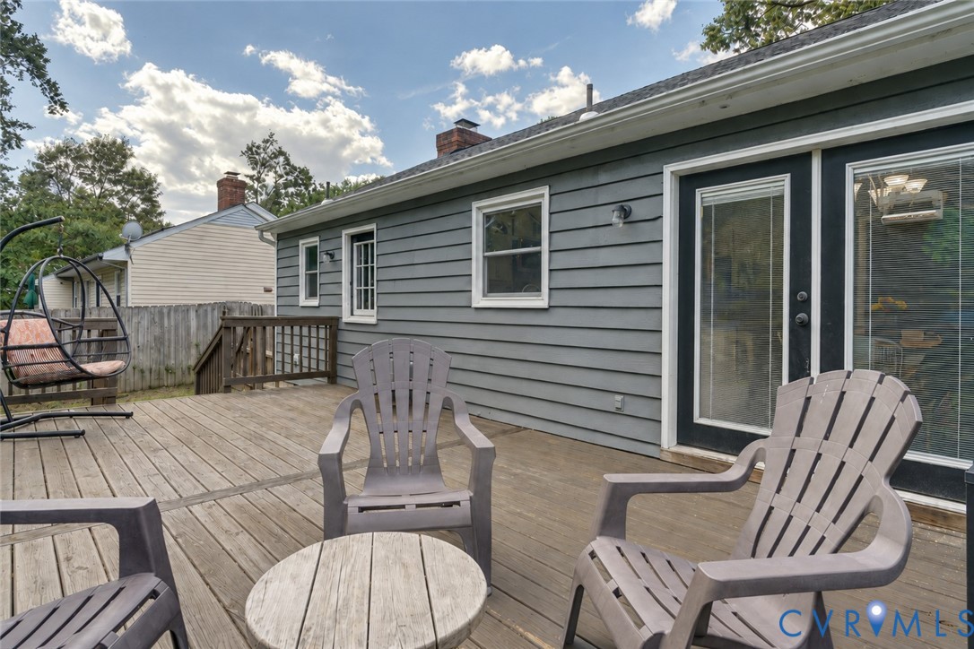 Wood-finish deck with exterior siding, multiple windows, and a glass-paneled entry door