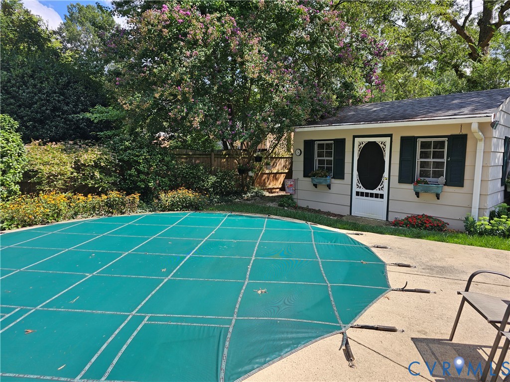 Paved patio area with a covered pool and surrounding landscaping Paved patio area with a covered pool and surrounding landscaping