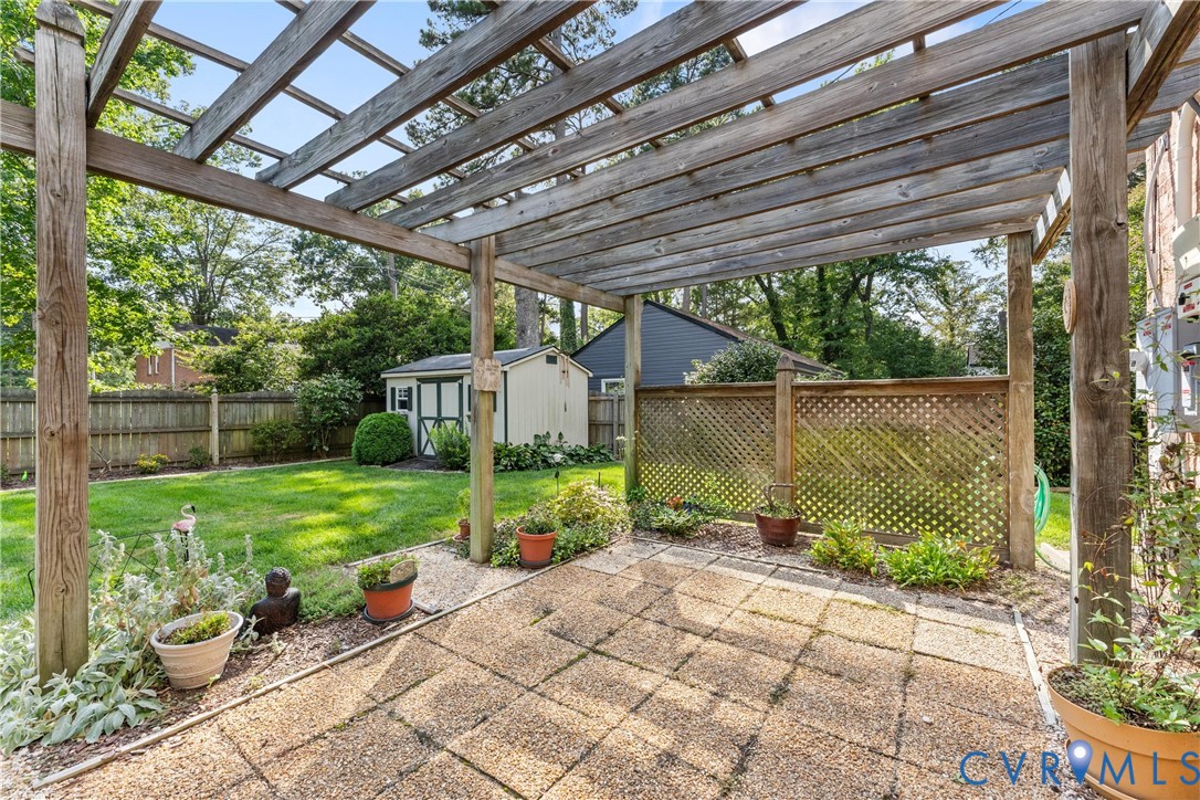 Patio featuring a wood pergola, paver flooring, and decorative lattice fencing