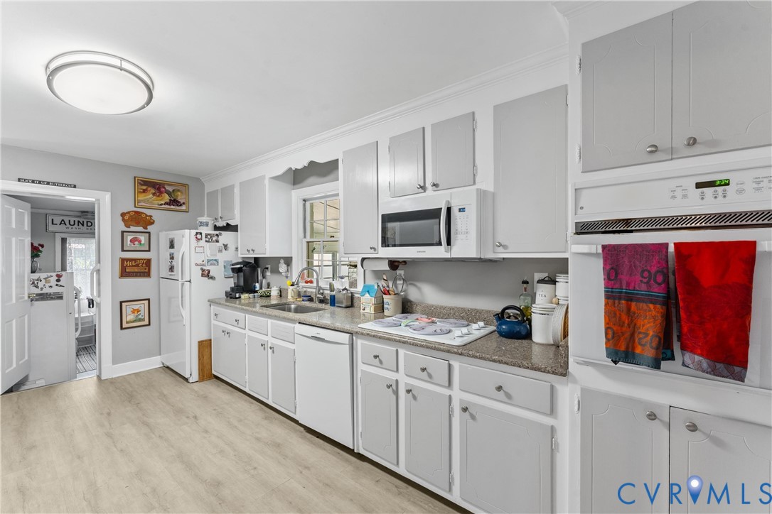Kitchen featuring light wood-finish flooring, white cabinetry, a built-in oven, and a built-in microwave