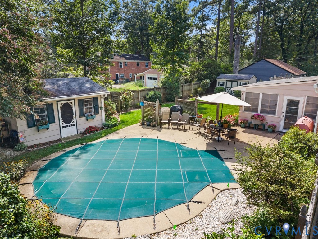 Outdoor swimming pool with a safety cover, concrete patio, a detached shed with window boxes, and a screened-in porch Outdoor swimming pool with a safety cover, concrete patio, a detached shed with window boxes, and a screened-in porch