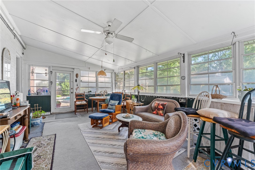 Enclosed porch featuring multiple windows, a ceiling fan, and sloped ceiling