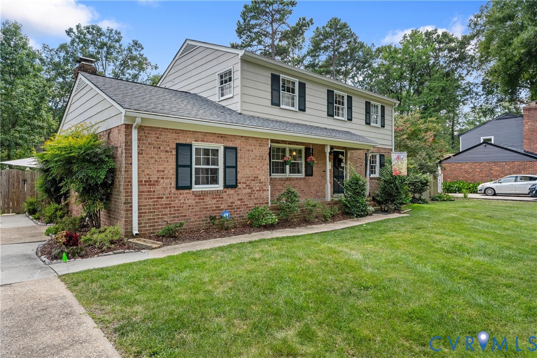 Traditional two-story residence featuring brick and siding exterior, a covered front porch, and a paved walkway Traditional two-story residence featuring brick and siding exterior, a covered front porch, and a paved walkway