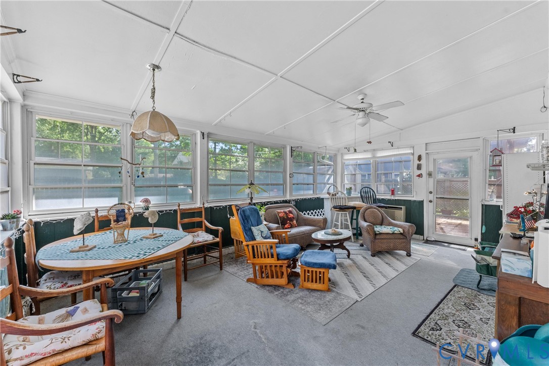Expansive sunroom featuring multiple large windows, a ceiling fan, and an exterior access door