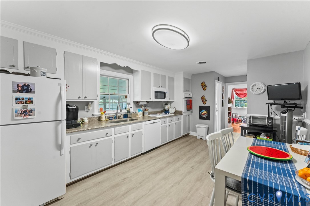 Kitchen featuring wood-finish flooring, light-toned cabinetry, light-toned countertops, a window over the sink, and ceiling-mounted lighting