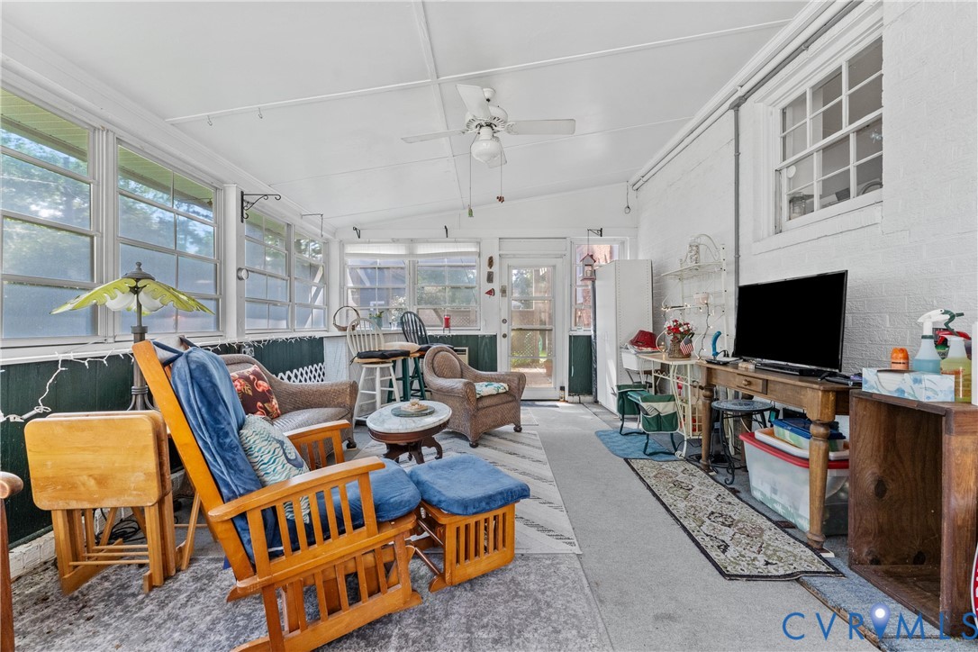 Sunroom featuring numerous windows, a ceiling fan, and concrete flooring