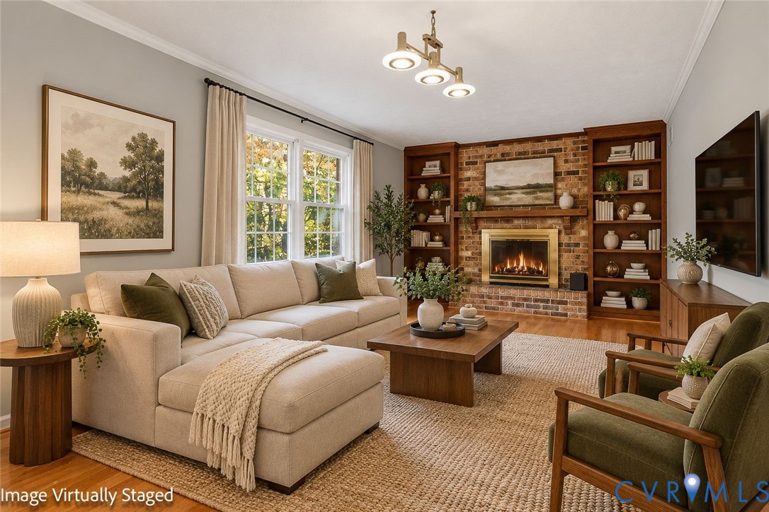 Living room featuring a floor-to-ceiling brick fireplace with a wood mantel, built-in wooden shelving, wood-finish flooring, and a multi-light chandelier