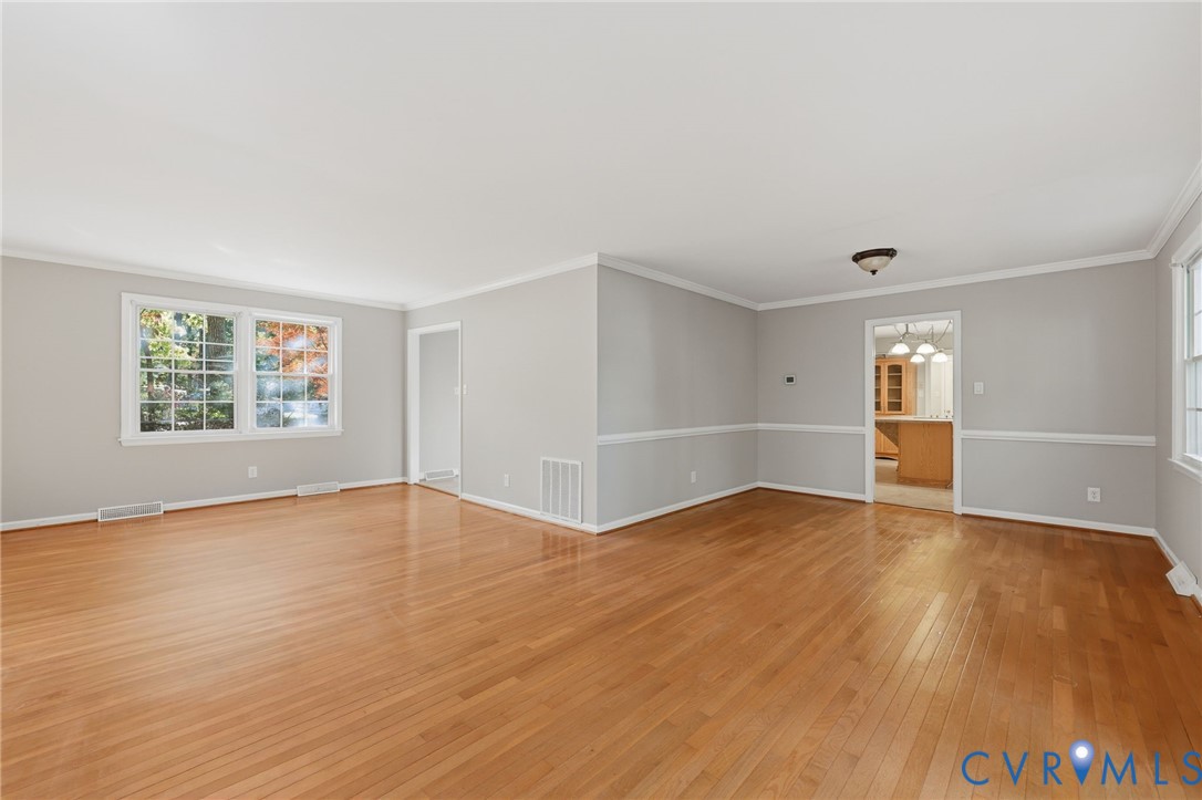 Neutral-toned interior featuring wood-finish flooring, crown molding, chair rail detailing, and multi-pane windows