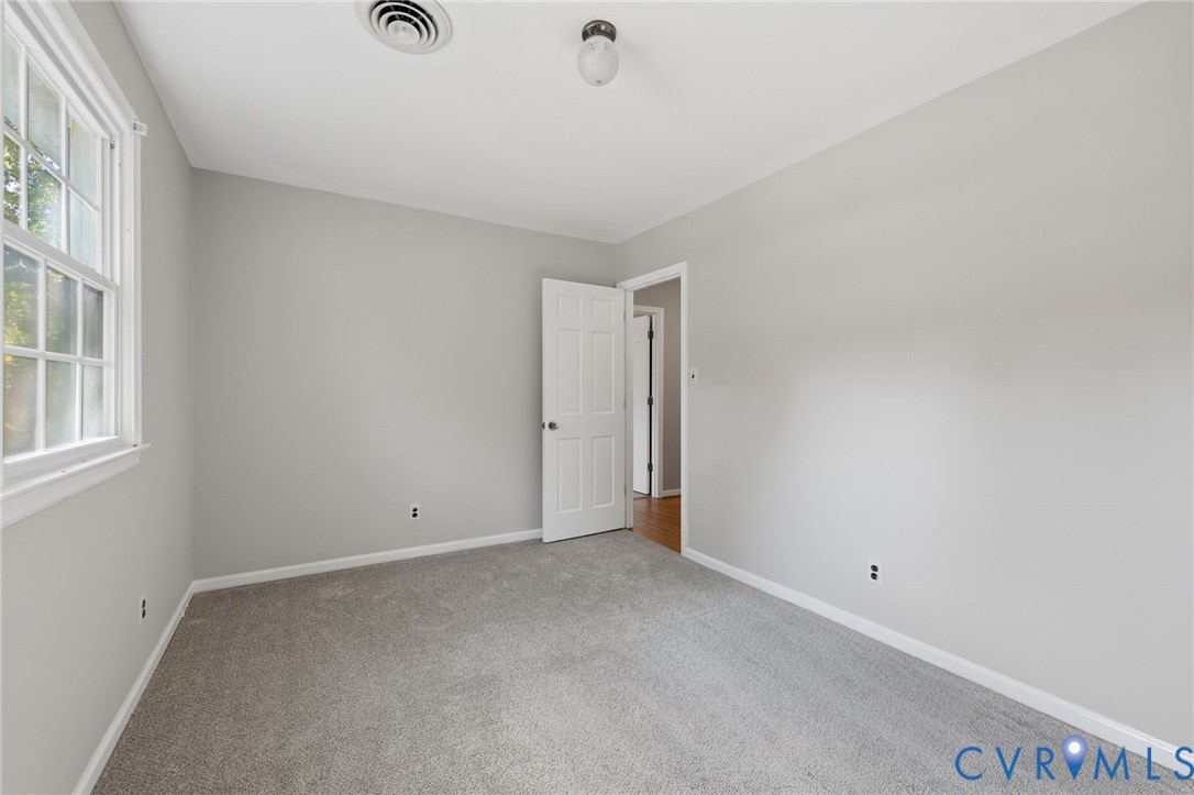 Neutral-toned interior featuring wall-to-wall carpeting, a six-panel interior door, and a single-hung window with muntin detailing