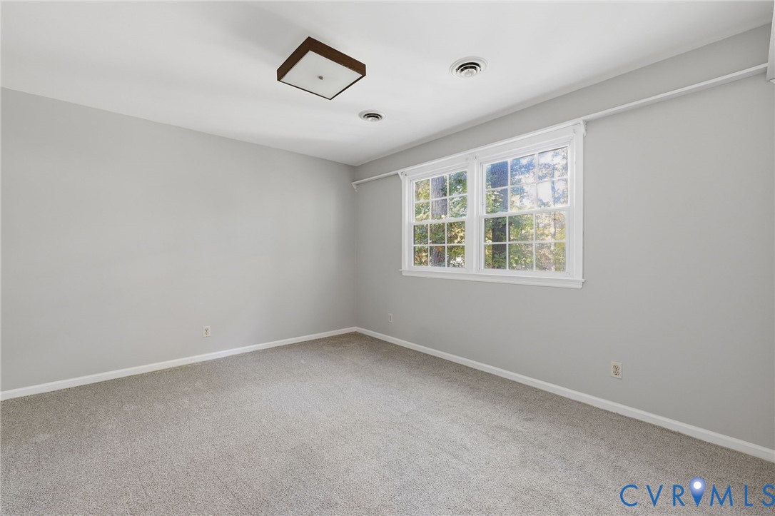 Neutral-toned walls, wall-to-wall carpeting, double-hung windows, and a flush-mount light fixture
