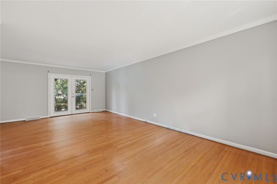 Open-concept interior featuring wood-finish flooring, neutral wall paint, and glass-paned double doors