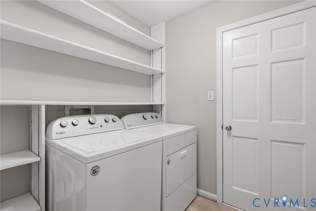 Utility room featuring white built-in shelving, tile flooring, and a six-panel door