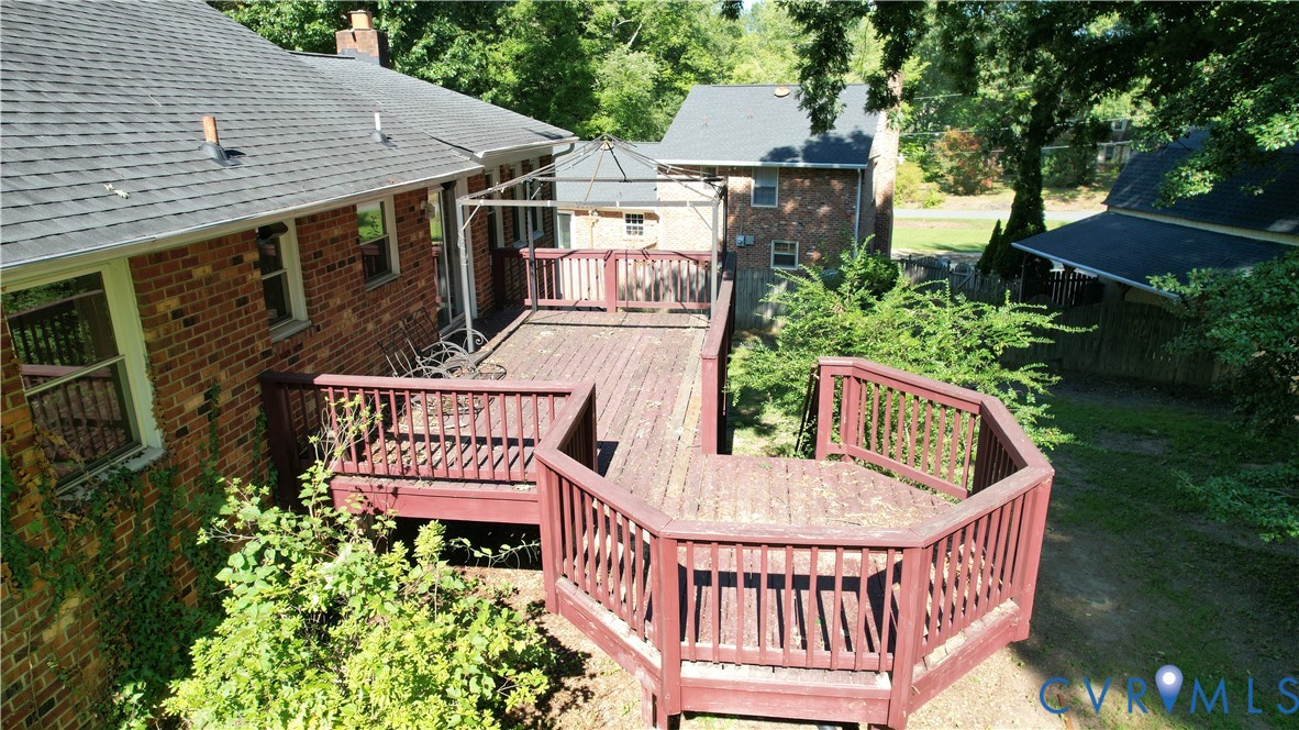 Expansive multi-level wood deck with a gazebo frame, brick exterior, and a shingle roof