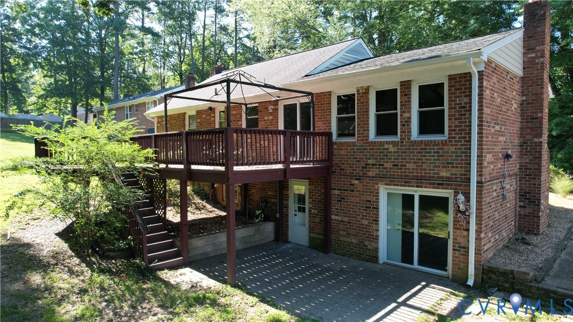 Multi-level exterior with brick siding, a raised deck, and a lower-level concrete patio