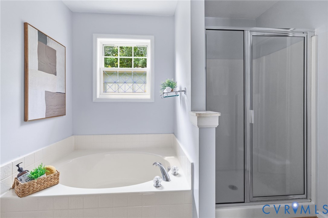 Built-in soaking tub with tile surround, framed window, and clear glass shower enclosure