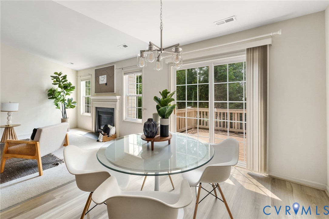 Light wood-finish flooring, a fireplace with a mantel, double windows, sliding glass doors, and a wood deck
